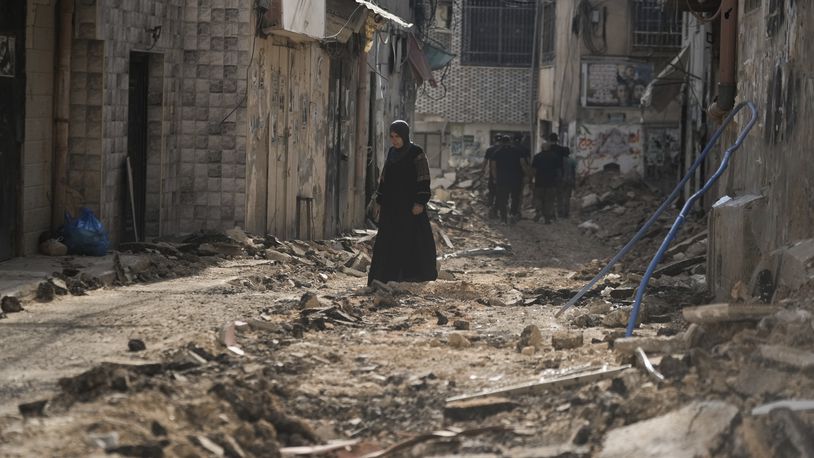 Palestinians walk on a damaged road following an Israeli military operation in the West Bank city of Jenin on Friday, Sept. 6, 2024. (AP Photo/Majdi Mohammed)