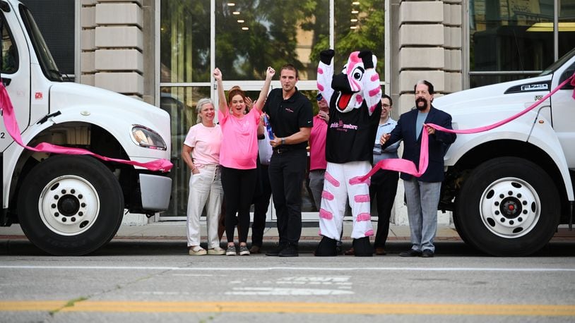 Drue Chrisman, a former Bengals punter and owner of the Pink Zebra Moving franchise in Lawrenceburg, Ind., expands into downtown Hamilton, Ohio. Pictured is the ribbon cutting in front of the Rentschler Building at the corner of High and Second streets. MICHAEL D. PITMAN/STAFF