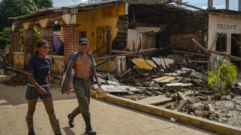 Residents walk past a house damaged by Hurricane John in Coyuca de Benitez, Guerrero state, Mexico, Monday, Sept. 30, 2024. (AP Photo/Felix Marquez)