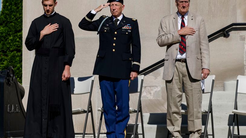 Father Edward Hoffman, left, Parade Grand Marshal retired Army Lt. Col. William Moeller, middle, and Hamilton Mayor Pat Moeller, stand during a wreath laying ceremony in front of the Soldiers, Sailors and Pioneers Monument before the Memorial Day Parade Monday, May 29, 2023 in Hamilton. NICK GRAHAM/STAFF