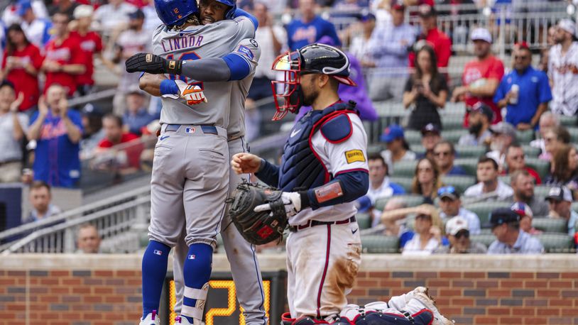 New York Mets' Francisco Lindor, left, and Starling Marte, center, celebrate at home plate after scoring in the ninth inning of a baseball game against the Atlanta Braves, Monday, Sept. 30, 2024, in Atlanta. (AP Photo/Jason Allen)