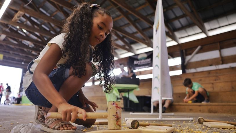 Sofia Snell, 6, cracks corn as she learns about agriculture during Farmertown at the Butler County Fair Thursday, July 25, 2024 in Hamilton. NICK GRAHAM/STAFF