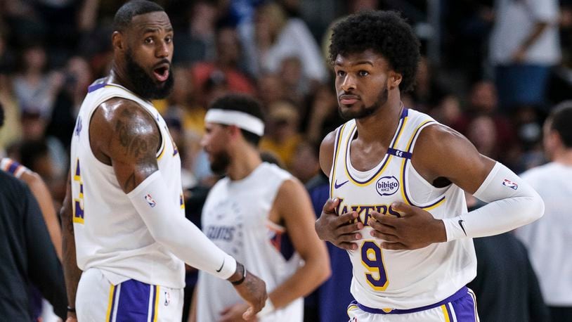 Los Angeles Lakers guard Bronny James (9), right, steps onto the court with Los Angeles Lakers forward LeBron James (23) during the first half of a preseason NBA basketball game Sunday, Oct. 6, 2024, in Palm Desert, Calif. (AP Photo/William Liang)