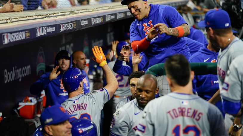 New York Mets' Pete Alonso, lower left, high fives a teammate after hitting an RBI sacrifice fly during the eighth inning of Game 1 of a baseball NL Division Series against the Philadelphia Phillies, Saturday, Oct. 5, 2024, in Philadelphia. (AP Photo/Chris Szagola)