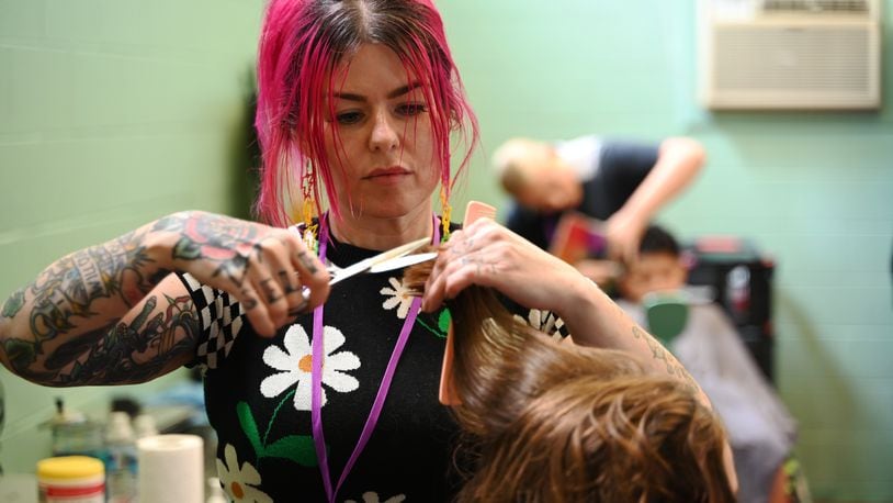 Biz Jarvis, owner of Hue Mane Salon in Hamilton, is giving back to the community when she offered free haircuts to the kids that attend the Boys and Girls Clubs of Hamilton on Grand Boulevard. She's pictured here giving a haircut to a girl at the Boys and Girls Club on Wednesday, July 31, 2024. MICHAEL D. PITMAN/STAFF