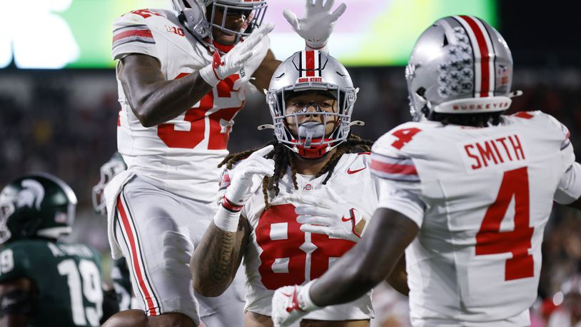 Ohio State tight end Gee Scott Jr., center, Ohio State running back TreVeyon Henderson, left, and Ohio State wide receiver Jeremiah Smith (4) celebrate Scott's touchdown during the first half of an NCAA college football game, Saturday, Sept. 28, 2024, in East Lansing, Mich. (AP Photo/Al Goldis)