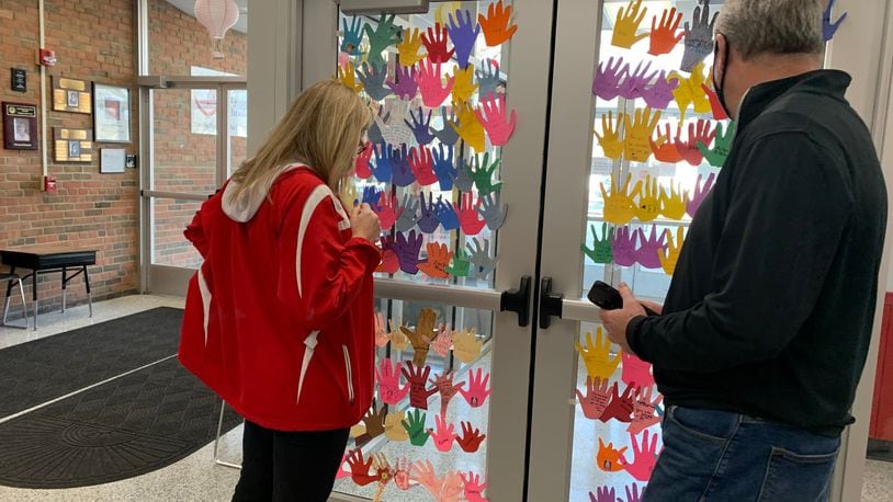 Fairfield West Elementary Principal Missy Muller was recently pleasantly shocked  when her school's nearly 800 students decorated the front lobby and office windows with paper cut outs of their hands adorned with emotional messages of support. Muller - left, reading some of the many messages - is battling a bone marrow disease and is leaving the city - and her job - temporarily for treatment. CONTRIBUTED