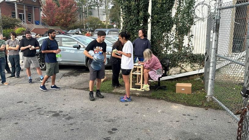 People wait to gather water at Mountain Valley Water in the aftermath of Hurricane Helene in West Asheville, N.C., Monday, Sept. 30, 2024 (AP Photo/Jeffrey Collins)