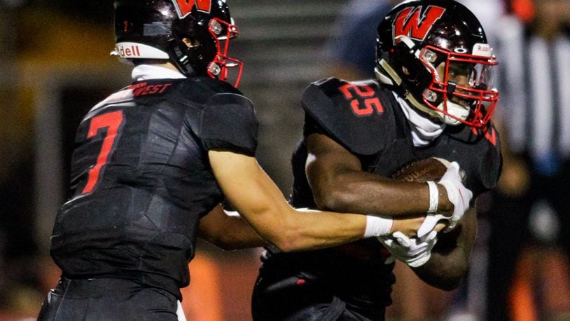 Lakota West quarterback Mitch Bolden, left, hands the ball off to running back Cameron Goode during their game against Hamilton Friday, Sept. 4, 2020 at Lakota West High School in West Chester Township. Lakota West won 40-13. NICK GRAHAM / STAFF