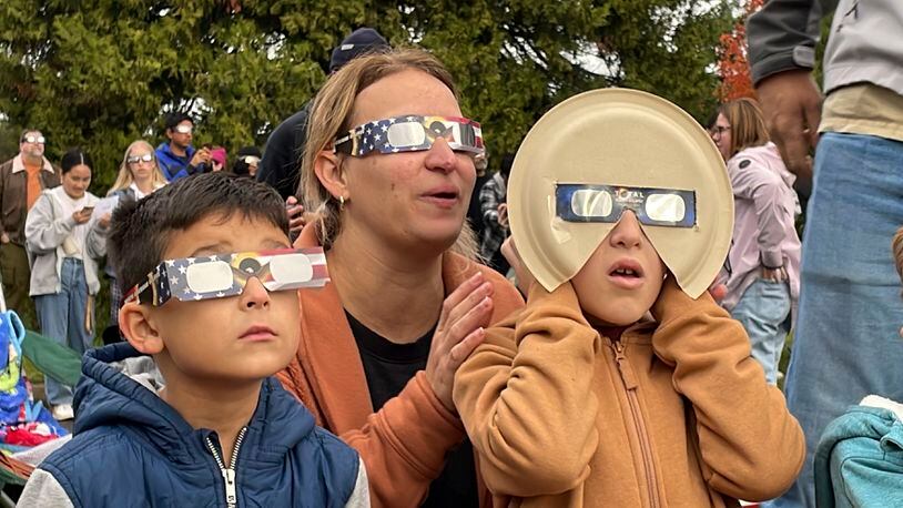 Samia Harboe, her son Logan and her friend's son wear eclipse glasses during totality of the annular solar eclipse in Eugene, Ore., on Saturday, Oct. 14, 2023. Her family came with glasses they'd made for the 2017 total eclipse and said they were excited to see another one. (AP Photo/Claire Rush)