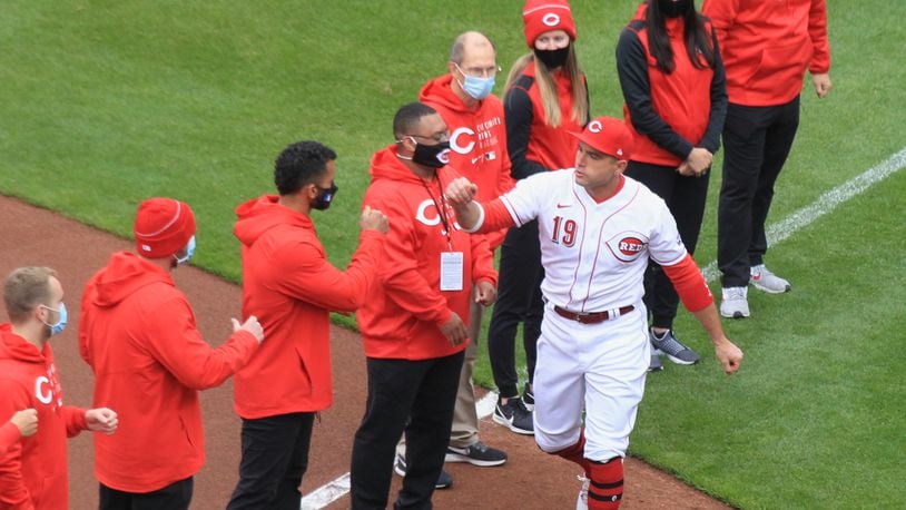 Joey Votto, of the Reds, slaps hands with members of the staff during a pregame ceremony on Opening Day on Thursday, April 1, 2021, at Great American Ball Park in Cincinnati. David Jablonski/Staff