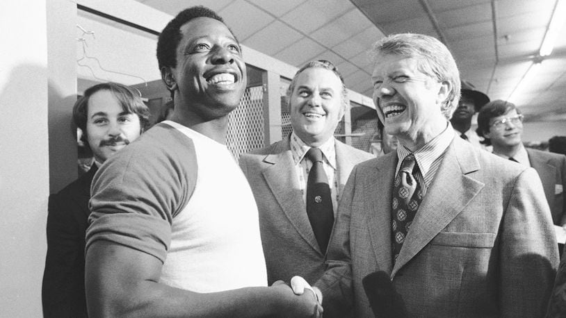 FILE - Georgia Gov. Jimmy Carter, right, and Delaware Gov. Sherman Tribbitt say hello to Atlanta Braves Hank Aaron, left, following a rain canceled game with the Los Angeles Dodgers in Atlanta, Ga., Sept. 27, 1973. (AP Photo, File)