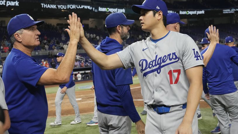 Los Angeles Dodgers' Shohei Ohtani (17) is congratulated by a coach at the end of a baseball game against the Miami Marlins, Thursday, Sept. 19, 2024, in Miami. (AP Photo/Marta Lavandier)