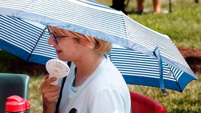 Sinclair Community College staff member Sam Kennedy tries to stay cool with a battery powered fan and a umbrella on a hot Thursday, Aug 29, 2024 at Tartan Lawn Party as part of the Welcome Week celebration for students. Tempatures reached a high of 93 degrees. MARSHALL GORBY\STAFF