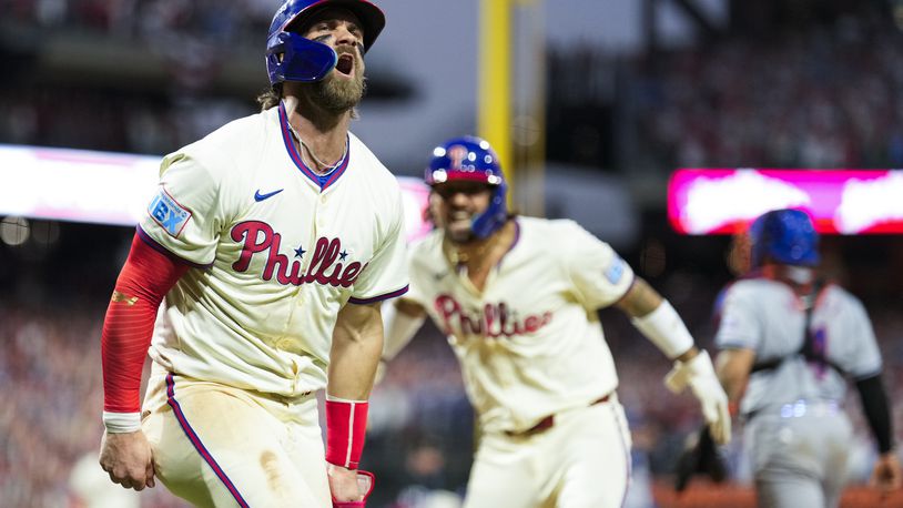 Philadelphia Phillies' Bryce Harper, left, and Nick Castellanos celebrate after scoringon a two-run triple hit by Bryson Stott during the eighth inning of Game 2 of a baseball NL Division Series against the New York Mets, Sunday, Oct. 6, 2024, in Philadelphia. (AP Photo/Matt Slocum)