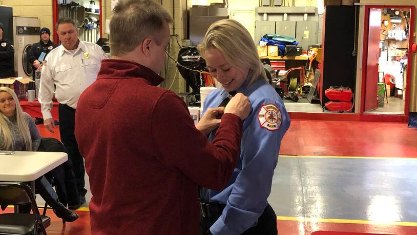 Celine Schank, 24, a 2015 Lakota West High School graduate, is pinned by her father, Thomas, Friday during a ceremony at Fire Headquarters. Fire Chief Paul Lolli looks on. RICK McCRABB/STAFF
