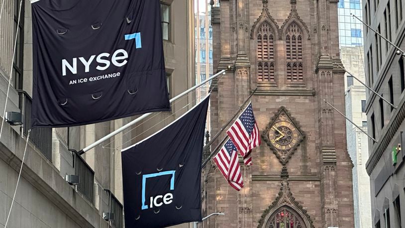 Flags fly on the side of the New York Stock Exchange with Trinity Church in the background on Wednesday, Aug. 28, 2024, in New York. (AP Photo/Peter Morgan)