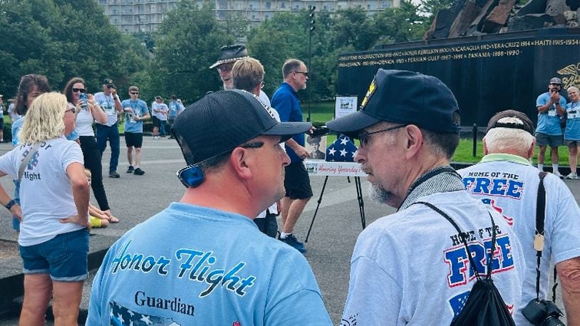 Stephen Lewis, 75, is a Vietnam veteran and Fairfield resident who on Aug. 10, 2024, took an Honor Flight trip out of the Dayton hub to Washington, D.C., with his son, Tim Lewis, of Fairfield. Pictured is the younger Lewis, left, talking to his dad in front of the World War II memorial. An easel in the background holds a photo of Stephen Lewis' dad, Earl E. Lewis, a WWII veteran and Fairfield resident who died in 2016. It was part of the Honor Flight's Honoring Yesterday's Heroes program. PROVIDED