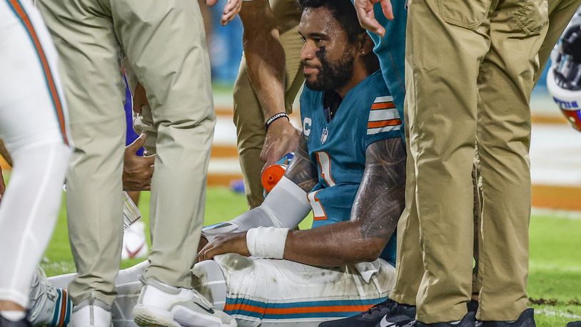 Miami Dolphins quarterback Tua Tagovailoa (1) sits on the field as he is attended to after an injury during the game against the Buffalo Bills in the second half of an NFL football game on Thursday, Sept. 12, 2024. (Al Diaz/Miami Herald via AP)