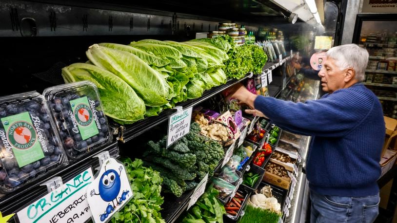 Tom Swing, store manager and an owner/member, stocks produce at Moon Co-op in Oxford. NICK GRAHAM/STAFF