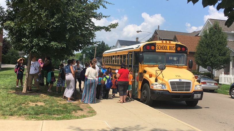 JEREMY P. KELLEY / STAFF ORIGINAL CUTLINE: Students board a school bus outside Ruskin Elementary school in Dayton as teachers and school staff monitor the area.