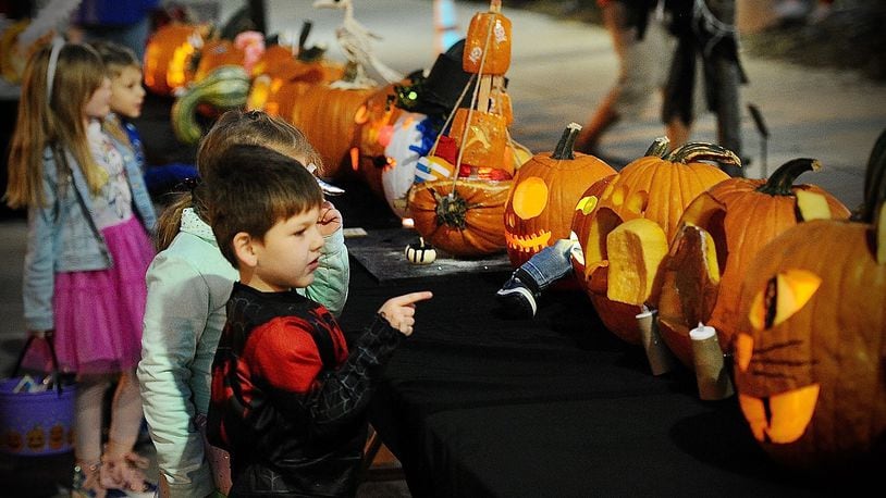Children look over the pumpkins in the pumpkin carving contest Saturday during the New Carlisle Halloween Night Market. Marshall Gorby/Staff