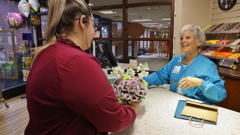 Health unit coordinator Miranda Meade, left, purchases flowers for a patient from hospital volunteer Cheryl Vajda at the gift shop Wednesday, July 10, 2024 at Kettering Health Hamilton. The gift was purchased through a new program funded by Fort Hamilton Hospital Foundation to allow employees to purchase gifts for patients. NICK GRAHAM/STAFF