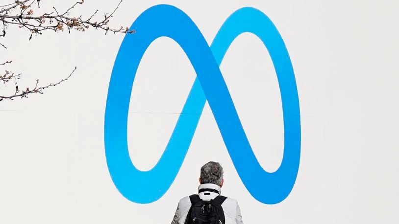 FILE - A person stands in front of a Meta sign outside of the company's headquarters in Menlo Park, Calif., March 7, 2023. (AP Photo/Jeff Chiu, File)