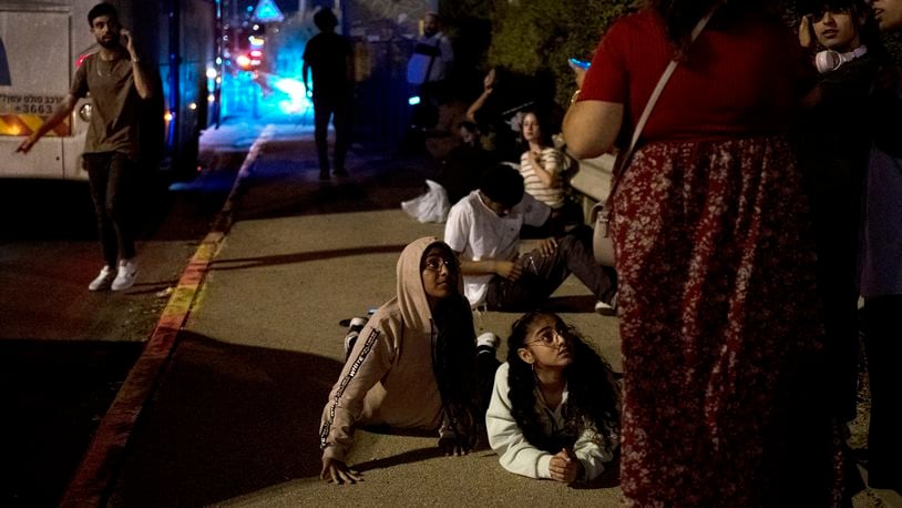 Israelis wait to re-board their bus after projectiles were launched from Iran are being intercepted in the skies over in Rosh HaAyin, Israel, Tuesday, Oct. 1, 2024. (AP Photo/Maya Alleruzzo)