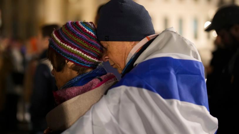 A man embraces a women at they attend the reading the names of the victims of the Hamas attack on Israel, during a commemoration to mark the first anniversary of the attack, at the Brandenburg Gate in Berlin, Germany, Monday, Oct. 7, 2024. (AP Photo/Markus Schreiber)