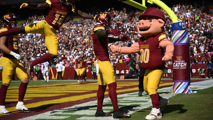 FILE - Washington Commanders running back Brian Robinson Jr., second from right, celebrates his touchdown with mascot Major Tuddy, right, during the first half of an NFL football game against the Cleveland Browns, Sunday, Oct. 6, 2024, in Landover, Md. Also seen is Commanders wide receiver Olamide Zaccheaus (14). (AP Photo/Nick Wass, File)