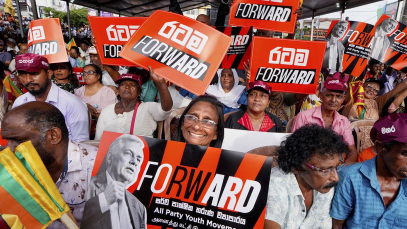 A woman supporter of Sri Lankan President and independent presidential candidate Ranil Wickremesinghe, holds a placard at an election rally in Minuwangoda, Sri Lanka, Tuesday, Sept. 17, 2024. (AP Photo/Rajesh Kumar Singh)