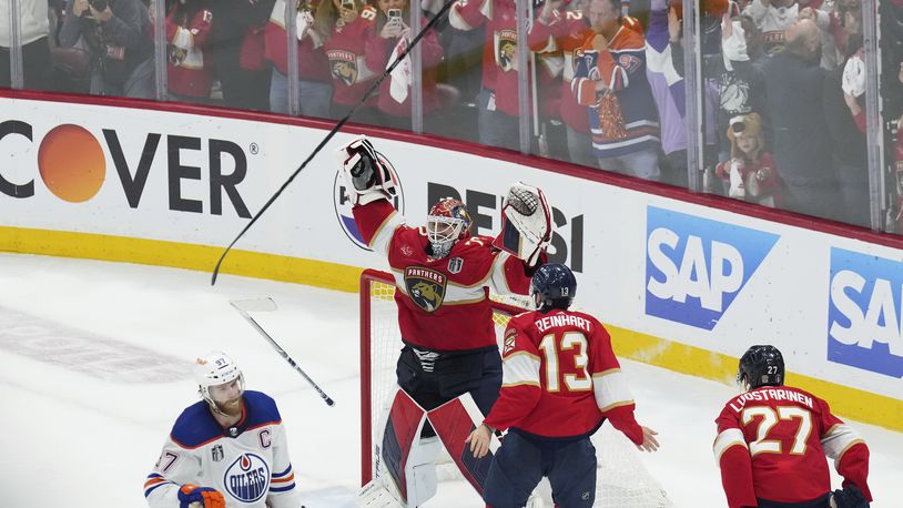 Florida Panthers goaltender Sergei Bobrovsky (72) and forward Sam Reinhart (13) celebrate after winning the NHL hockey Stanley cup as Edmonton Oilers forward Connor McDavid (97) looks on after Game 7 of the NHL hockey Stanley Cup Final in Sunrise, Fla., Monday, June 24, 2024. (Nathan Denette/The Canadian Press via AP)