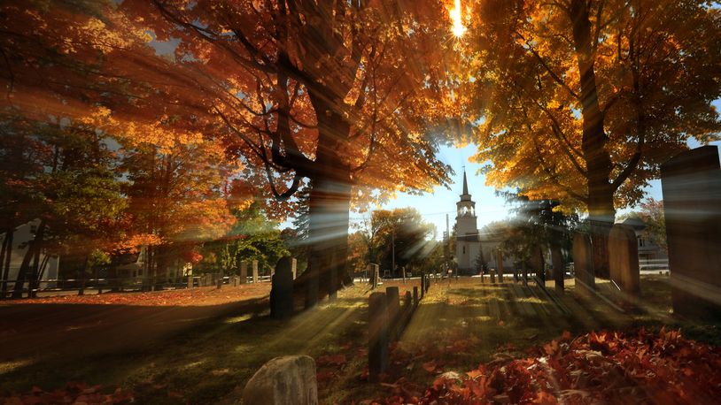 FILE - In this photo taken with a slow shutter speed, autumn's colors peak on hardwood trees in a cemetery near the Congregational Church, Monday, Oct. 10, 2016, in Cumberland, Maine. (AP Photo/Robert F. Bukaty, File)