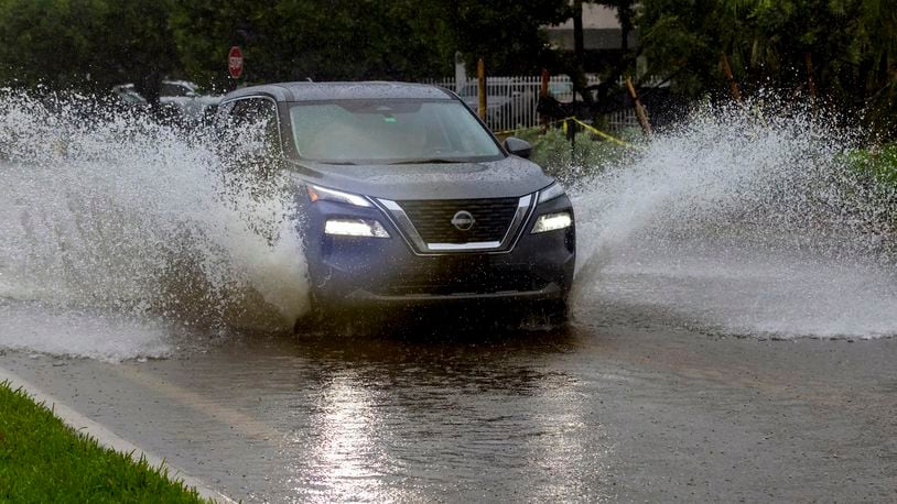 A car crosses the flooded road caused by heavy rain on North Bay Rd in Sunny Isles Beach, Fla., Tuesday, June 11, 2024. (David Santiago/Miami Herald via AP)