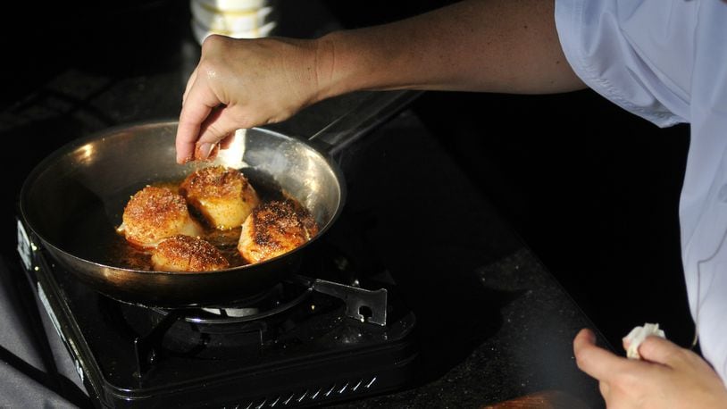 Executive Chef Michelle Brown of Jag's Steak & Seafood in West Chester Twp. performs a cooking demonstration on Tuesday, Aug. 18, 2015, at the Lindner Family Tennis Center during the Western & Southern Open in Mason, Ohio. She prepared caramelized chimichurri diver scallop over citrus arugula salad. (MICHAEL D. PITMAN/STAFF)