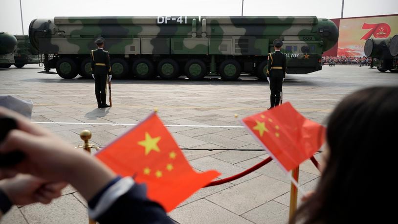 FILE - Spectators wave Chinese flags as military vehicles carrying DF-41 nuclear ballistic missiles roll during a parade to commemorate the 70th anniversary of the founding of Communist China in Beijing on Oct. 1, 2019. (AP Photo/Mark Schiefelbein, File)