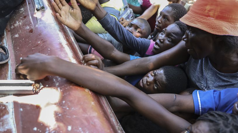 People displaced by armed attacks receive food from a nongovernmental organization in Saint-Marc, Haiti, Sunday, Oct. 6, 2024. (AP Photo/Odelyn Joseph)