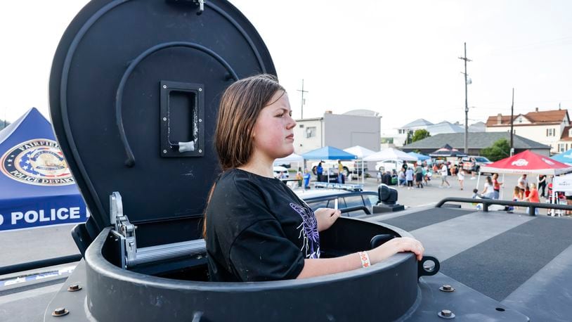 Angelica Hernandez, 13, pokes her head out of the top of a SWAT vehicle in this Journal-News file photo during an open house for Hamilton Police Department on Thursday, Aug. 3, 2023. Hamilton police and fire departments, neighboring police departments, and other community groups had games, food and canine demonstrations for attendees.  NICK GRAHAM/STAFF