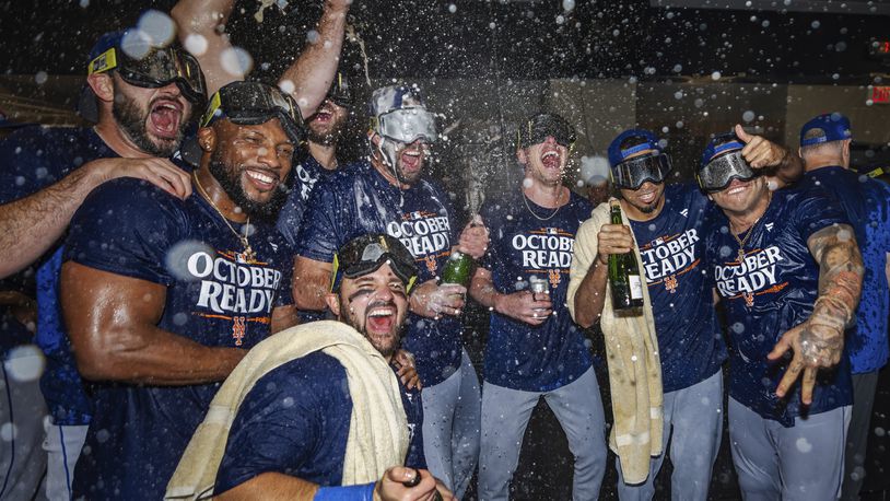 The New York Mets celebrate in the locker room after clinching a wild-card playoff berth after the second baseball game of a doubleheader against the Atlanta Braves, Monday, Sept. 30, 2024, in Atlanta. (AP Photo/Jason Allen)