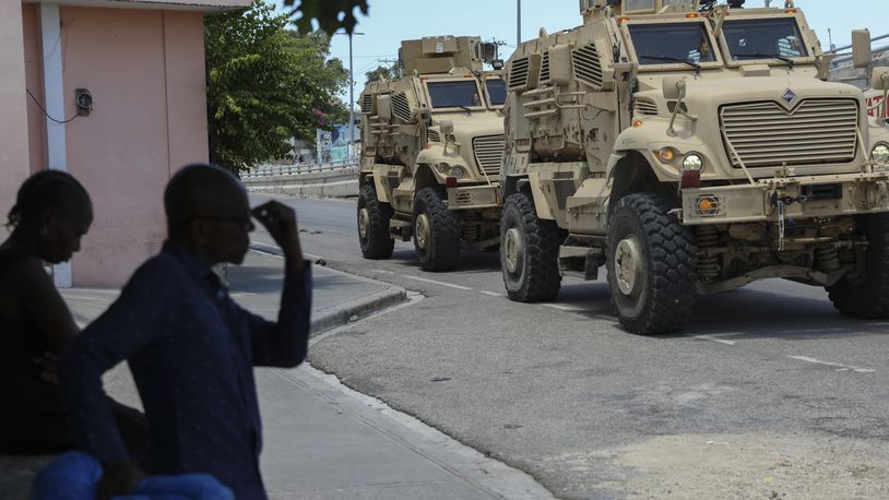 Kenyan police officers, part of a UN-backed multinational force, drive past residents in armored vehicles on the streets of Port-au-Prince, Haiti, Wednesday, Sept. 4, 2024. (AP Photo/Odelyn Joseph)