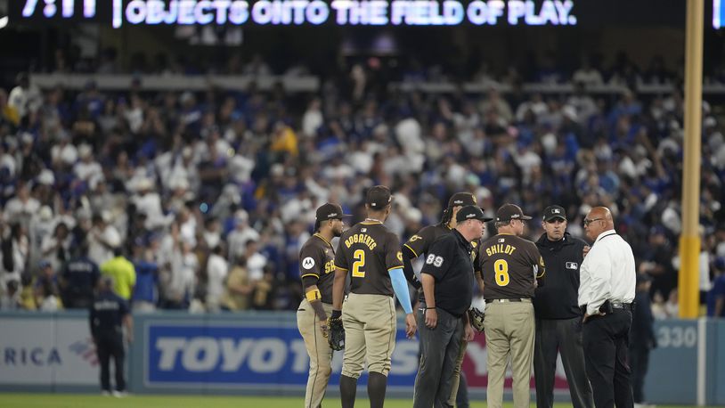 San Diego Padres manager Mike Shildt (8) and players talk to umpires after items were thrown on the field by fans during the seventh inning in Game 2 of a baseball NL Division Series against the Los Angeles Dodgers, Sunday, Oct. 6, 2024, in Los Angeles. (AP Photo/Ashley Landis)