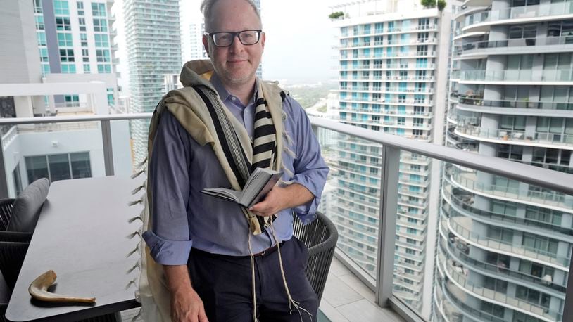 Daniel Gammerman poses for a photo on his balcony where he sometimes prays as he prepares to worship at home for the Jewish High Holy Days, Thursday, Sept. 26, 2024, in Miami. (AP Photo/Wilfredo Lee)