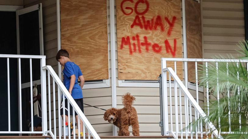 Noah Weibel and his dog Cookie climb the steps to their home as their family prepares for Hurricane Milton on Monday, Oct. 7, 2024, in Port Richey, Fla. (AP Photo/Mike Carlson)