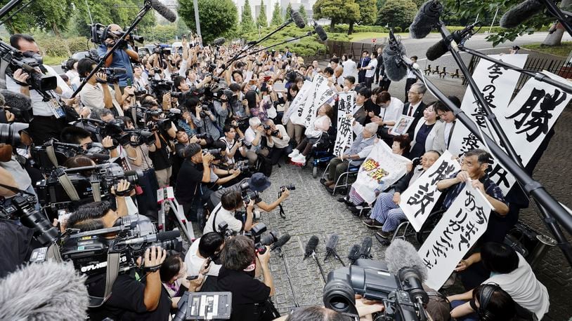 The plaintiffs, their lawyers and supporters hold the signs reading "Winning lawsuit" outside the Supreme Court after in Tokyo, Japan, Wednesday, July 3, 2024. Japan’s Supreme Court, in a landmark decision Wednesday, ordered the government to pay compensation to dozens of victims who were forcibly sterilized in the 1950s to 1970s under a now-defunct Eugenics Protection Law that was designed to eliminate offsprings of people with handicaps. (Kyodo News via AP)