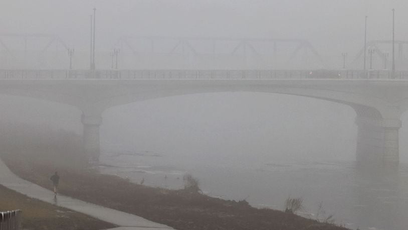 A person jogs on the bike path along the Great Miami River near the High-Main Bridge. Morning fog decreased visibility Wednesday morning, Jan. 24, 2024 in Hamilton. NICK GRAHAM/STAFF