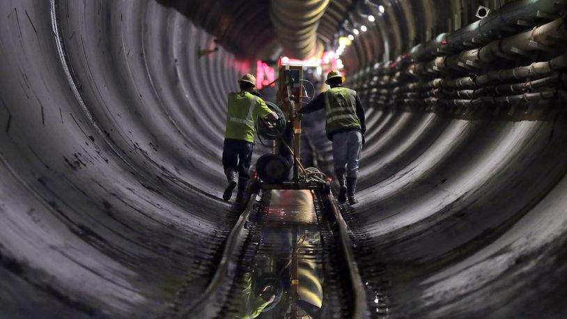 FILE - Tunnel workers push equipment up a rail track to a machine boring a 2.5-mile bypass tunnel for the Delaware Aqueduct in Marlboro, N.Y., May 16, 2018. (AP Photo/Julie Jacobson, File)