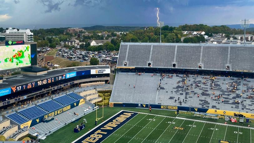 A lightning strike is shown in the distance above Mountaineer Field during an NCAA college football game between Kansas and West Virginia in Morgantown, W.Va., Saturday, Sept. 21, 2024. (AP Photo/John Raby)