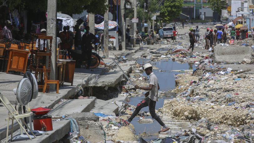 A man crosses a storm drain filled with trash in Port-au-Prince, Haiti, Friday, Sept. 13, 2024. (AP Photo/Odelyn Joseph)