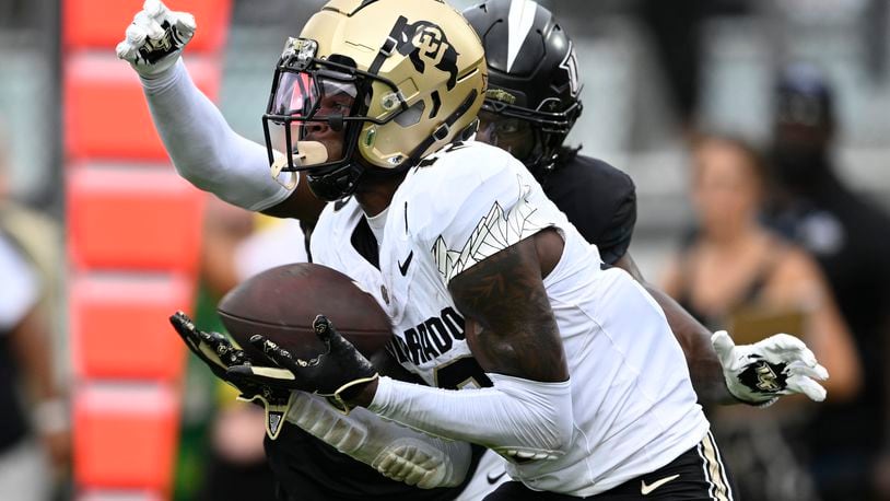 Colorado wide receiver Travis Hunter (12) catches a pass in the end zone for a 23-yard touchdown with Central Florida defensive back Brandon Adams behind him during the first half of an NCAA college football game, Saturday, Sept. 28, 2024, in Orlando, Fla. (AP Photo/Phelan M. Ebenhack)